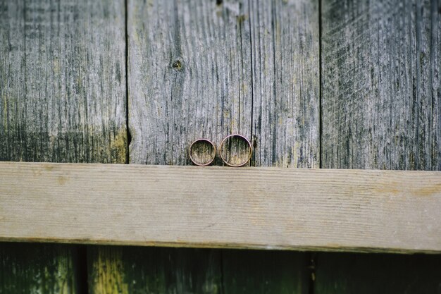 Zwei goldene Eheringe auf einem Stück Holz. Rustikales, stilvolles Foto.