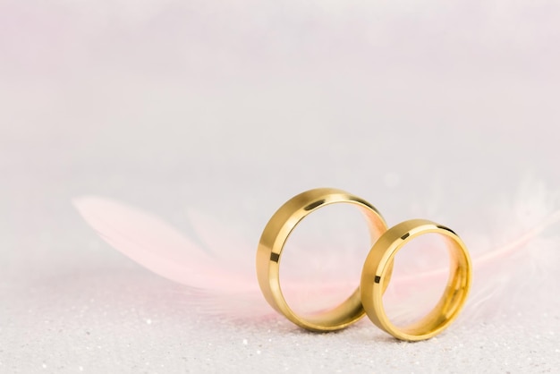 Zwei goldene Eheringe und leichte Engelsfeder sanfter weicher Hintergrund für die Ehe Vintage getönt