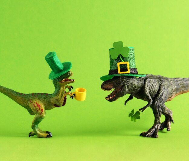 Zwei grüne Dinosaurier in grünen Hüten mit Bier und Kleeblättern feiern den St. Patrick's Day