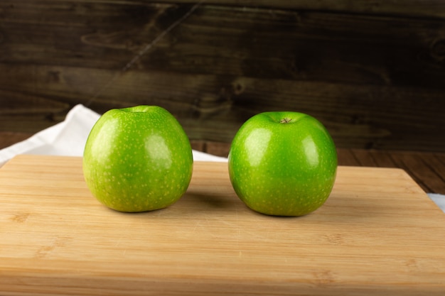 Zwei grüne frische Äpfel auf einem Holzbrett