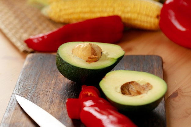 Zwei Hälften Avocado und roter Pfeffer auf Holzschneidebrett auf Tisch