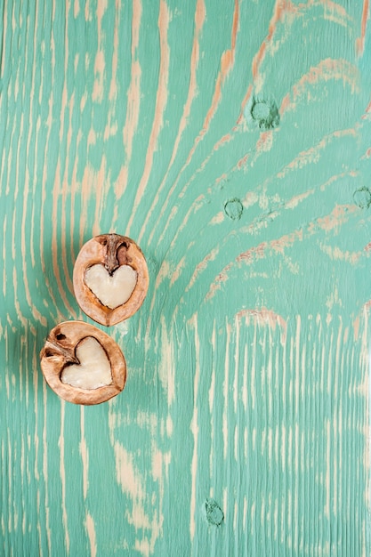 Zwei Hälften der Walnuss als Inneres liegen auf hellgrünem Holztisch mit Streifen und squiggly Flecken.