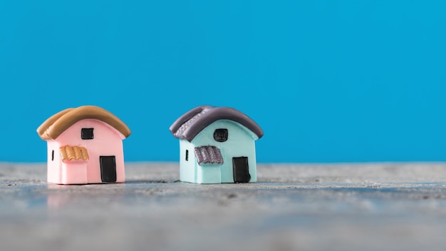 Zwei Häuser auf Holztisch auf blauer Oberfläche