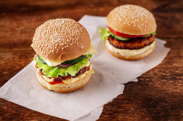 Zwei Hamburger auf einem hölzernen Hintergrund Großer und kleiner Cheeseburger Hamburger Tag