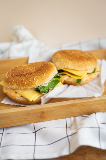 Zwei Hamburger liegen auf einem Holztablett mit einer weißen Serviette