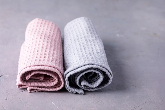 Zwei Handtücher tolled Up auf einem grauen Hintergrund Rosa und graue Handtücher horizontal