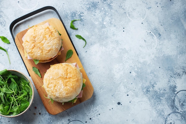 Zwei hausgemachte Sandwiches mit Schinkenkäse und Rucola auf einem Betontisch