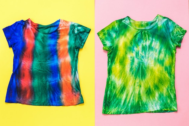 Zwei helle Tie-Dye-T-Shirts auf zweifarbigem Hintergrund Flach lag