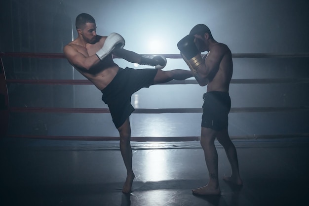 Zwei hemdlose muskulöse Männer kämpfen im Boxring gegen Kickboxen