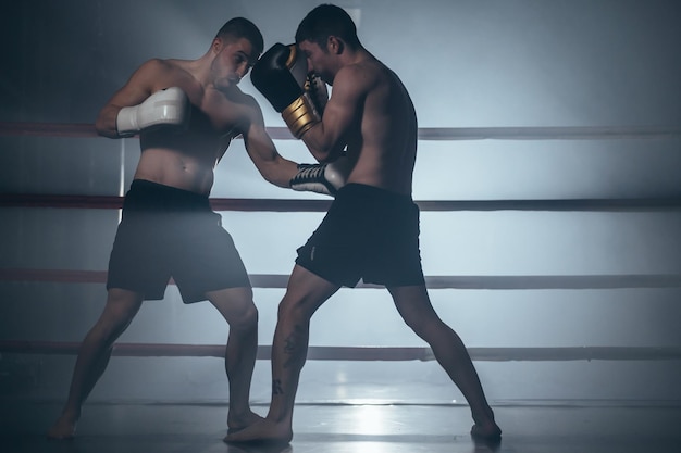 Zwei hemdlose muskulöse Männer kämpfen im Boxring gegen Kickboxen