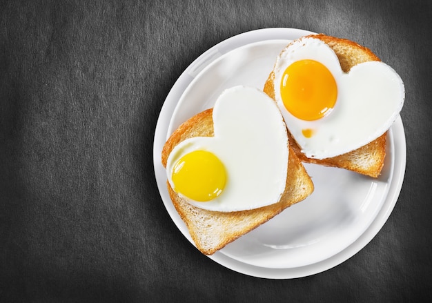 Zwei herzförmige Spiegeleier und gebratener Toast