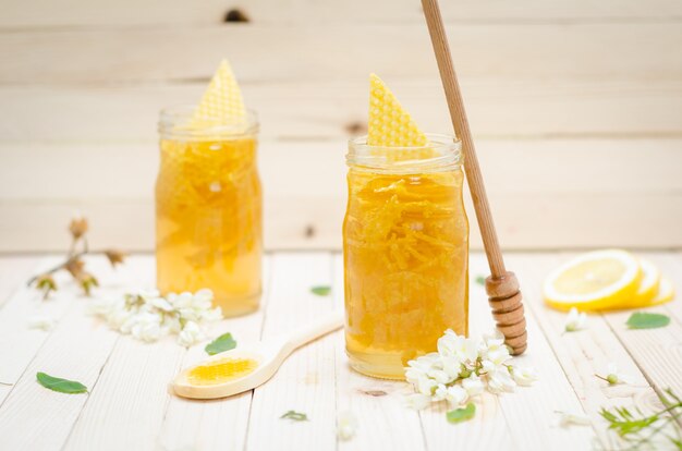 Zwei Heuschrecken-Honig-Retro- Gläser mit Heuschreckenblüten und -zitrone auf Retro- Holztisch. Nahansicht