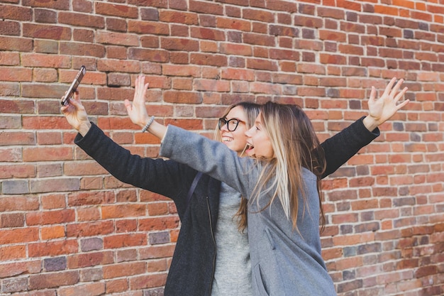 Zwei Hipster-Freundinnen, die ein Selbstfoto für soziale Netzwerke in der städtischen Hintergrundfreundschaft machen