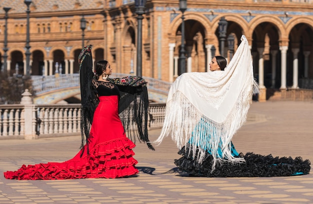 Zwei hispanische Frauen in Flamenco-Kleidung tanzen auf dem spanischen Platz in Sevilla