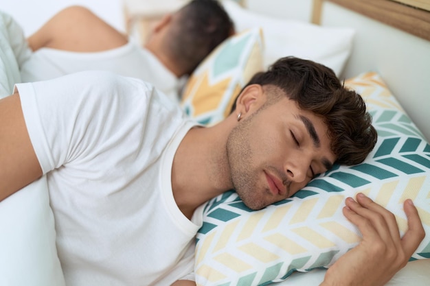 Zwei hispanische Männer liegen auf dem Bett und schlafen im Schlafzimmer