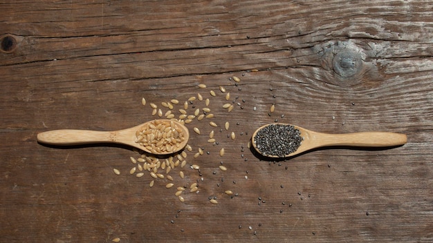 Zwei Holzlöffel mit Samen auf Holzhintergrund