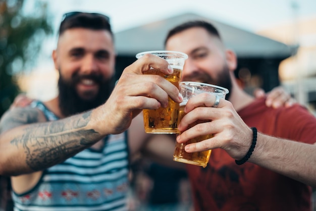 Zwei hübsche Freunde trinken Bier und haben Spaß beim Musikfestival