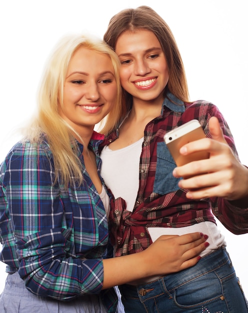 Zwei hübsche Hipster-Mädchen, die Selfie machen. Isoliert auf weißem Hintergrund.