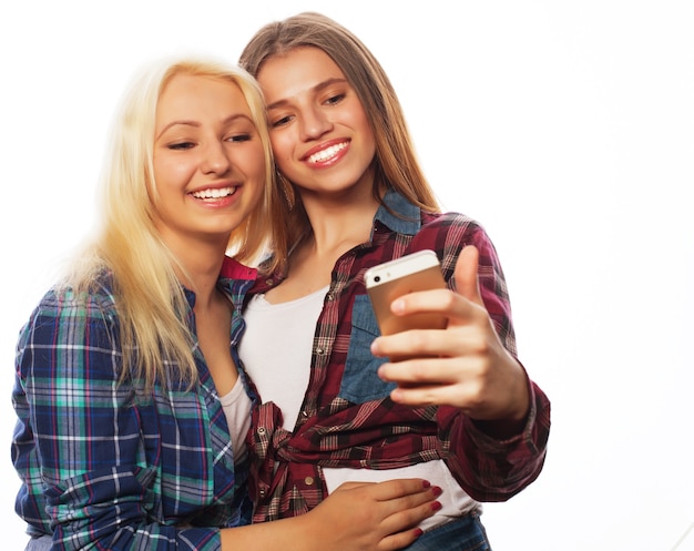 Zwei hübsche Hipster-Mädchen, die Selfie machen. Isoliert auf weißem Hintergrund.