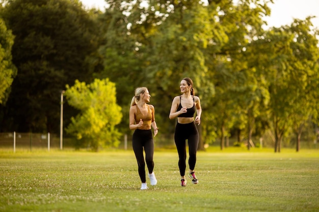 Zwei hübsche junge Frauen laufen im Park