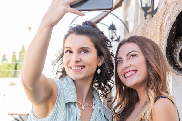 Zwei hübsche junge Mädchen im Urlaub lachen und machen ein Selfie