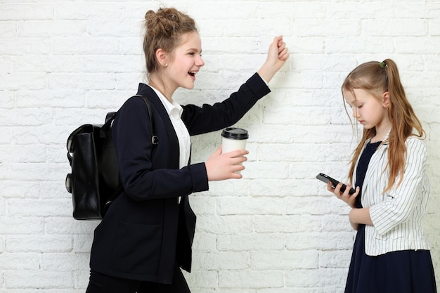 zwei hübsche junge Schulmädchen im Teenageralter, die Spaß haben, glücklich lächelnd auf weißem Hintergrund