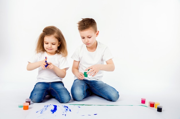 Zwei hübsche Kinderfreunde Jungen und Mädchen zeichnen Bilder von Farben