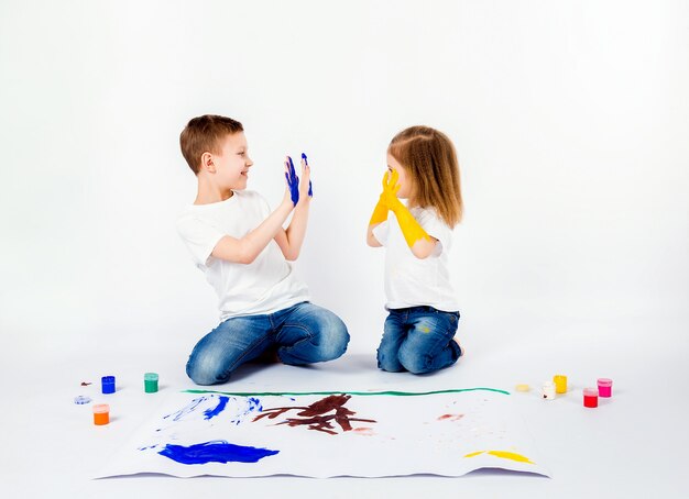 Zwei hübsche Kinderfreunde Jungen und Mädchen zeichnen Bilder von Farben