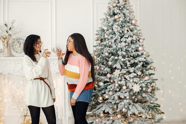 Zwei indische Mädchen mit Brille stehen in der Nähe des Weihnachtsbaums