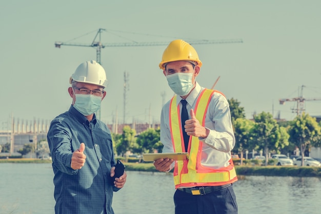 Zwei Ingenieur in Gesichtsmaske sprechen Projektplanung auf Baustellenkonstruktion