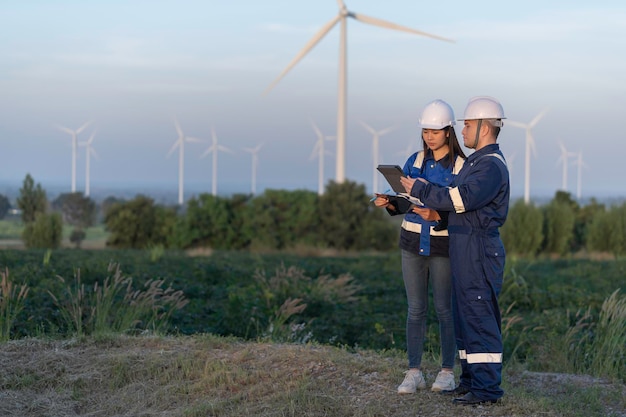 Zwei Ingenieure arbeiten und halten den Bericht auf einem Windturbinenbauernhof Power Generator Station auf dem BergThailand Menschen Techniker Mann und Frau diskutieren über die Arbeit