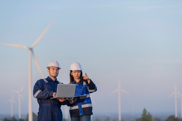 Zwei Ingenieure arbeiten und halten den Bericht auf einem Windturbinenbauernhof Power Generator Station auf dem BergThailand Menschen Techniker Mann und Frau diskutieren über die Arbeit