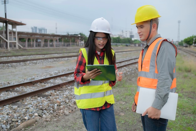 Zwei Ingenieure, die am Bahnhof arbeiten, arbeiten glücklich zusammen, helfen sich gegenseitig, das Problem zu analysieren, beraten sich über Entwicklungsrichtlinien