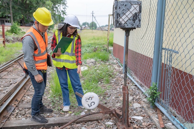 Zwei Ingenieure, die am Bahnhof arbeiten, arbeiten glücklich zusammen, helfen sich gegenseitig, das Problem zu analysieren, beraten sich über Entwicklungsrichtlinien