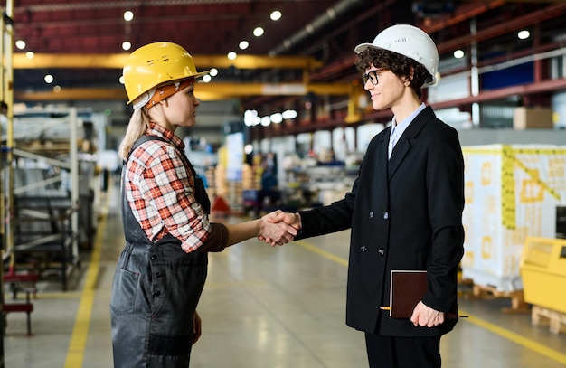 Zwei Ingenieure einer großen modernen Fabrik schütteln sich die Hände, nachdem sie sich geeinigt haben