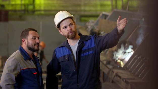 Zwei Ingenieure in Schutzuniform inspizieren Industriemaschinen im Werk