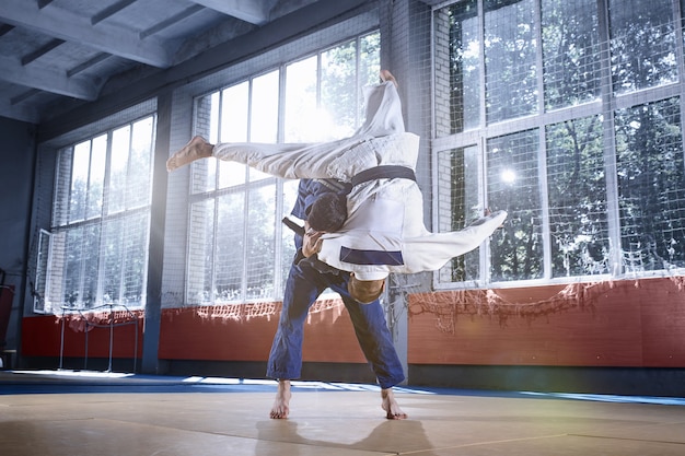 Zwei Judo-Kämpfer, die technische Fähigkeiten beim Üben von Kampfkünsten in einem Kampfclub zeigen. Die beiden passen Männer in Uniform. Kampf, Karate, Training, Kunst, Athlet, Wettkampfkonzept