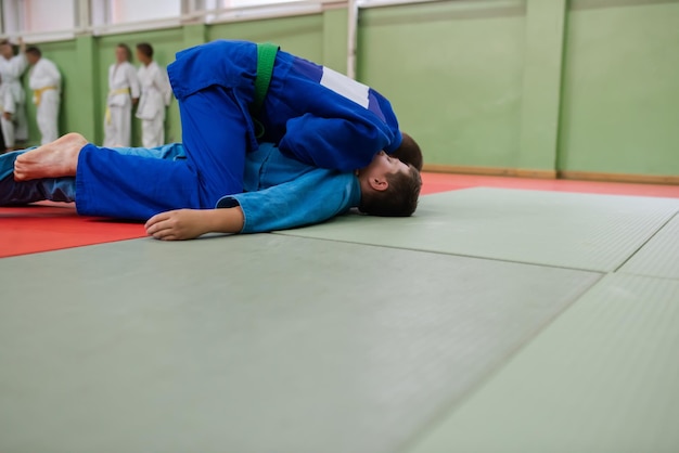 Zwei Judo-Kämpfer, die technische Fähigkeiten zeigen, während sie Kampfkunst in einem Kampfclub praktizieren Die beiden fitten Männer in Uniform kämpfen Karate-Trainingssportler-Wettkampfkonzept Selektiver Fokus