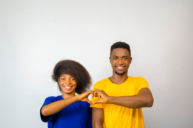 Zwei junge afrikanische Paare getrennt über weißem Hintergrund taten beide ein Liebeszeichen