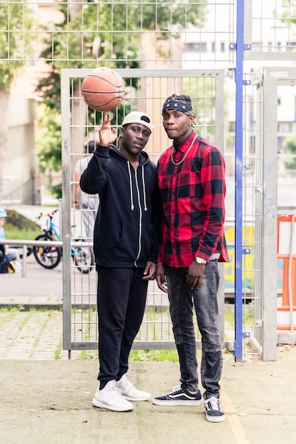 Zwei junge afroamerikanische Männer, die draußen am Basketballplatz aufwerfen