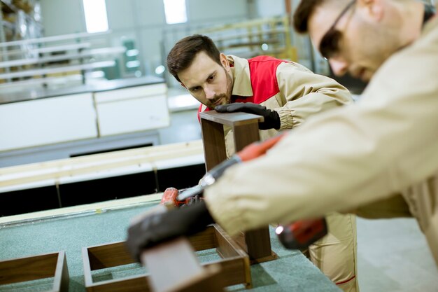 Zwei junge Arbeitnehmer, die Möbel in der Fabrik zusammenbauen