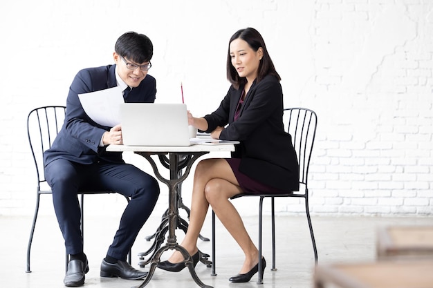 Zwei junge asiatische Frau und Mann, die mit Computer-Laptop arbeiten Junge asiatische Startup Kleinunternehmer und Frau glücklich mit Laptop Asian Businessman and Businesswoman