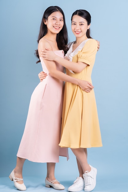 Zwei junge asiatische Frauen, die Kleid auf blauem Hintergrund tragen