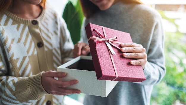 Zwei junge asiatische Frauen, die zusammen eine Geschenkbox öffnen