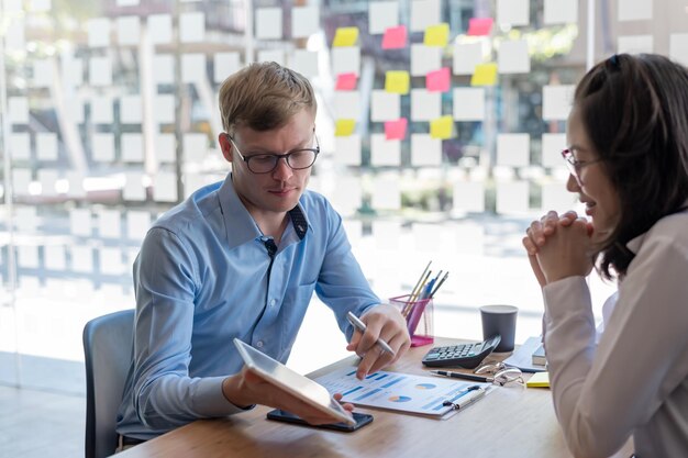 Foto zwei junge asiatische geschäftsleute sitzen da und diskutieren über geschäftsprojekte und investitionsgeschäfte