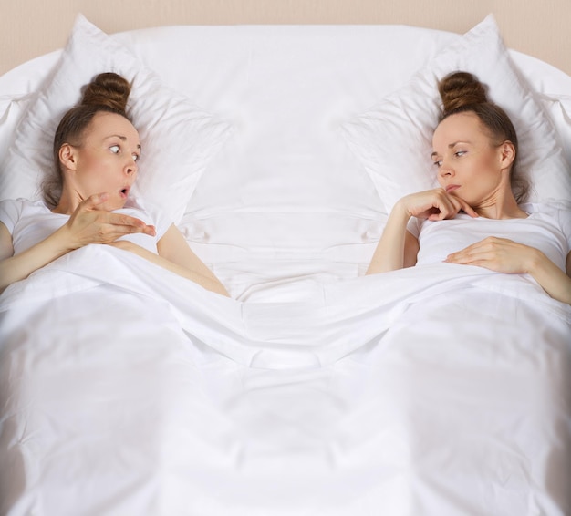 Zwei junge Damen zwischen 30 und 40 Jahren bleiben überrascht im Bett liegen. Nahaufnahme