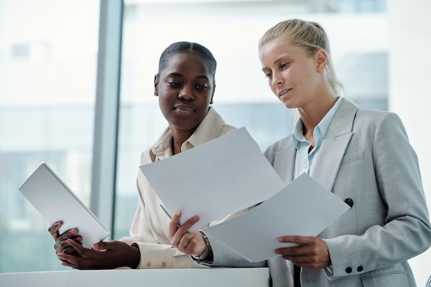 Zwei junge erfolgreiche Geschäftsfrauen, die Finanzdokumente durchsehen