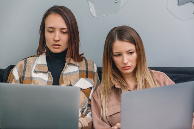 Zwei junge Frauen, die an Laptops arbeiten