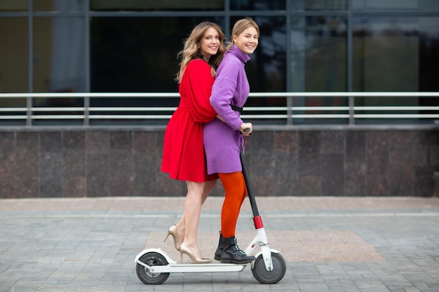 Zwei junge Frauen, die auf einem Elektroroller in der Stadt fahren