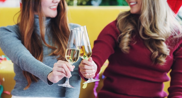 Zwei junge Frauen, die Champagnergläser halten und einen Toast, mit lächelndem Gesicht geben. Feier- und Begrüßungskonzepte